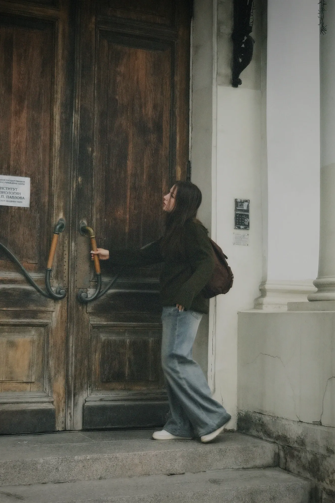 A person opening a large wooden door